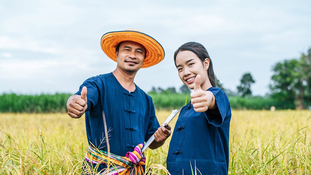 Portrait Asian Middle aged man wearing straw hat and loincloth write on clipboard with young woman farmer, they are thump up and smile with happiness copy space