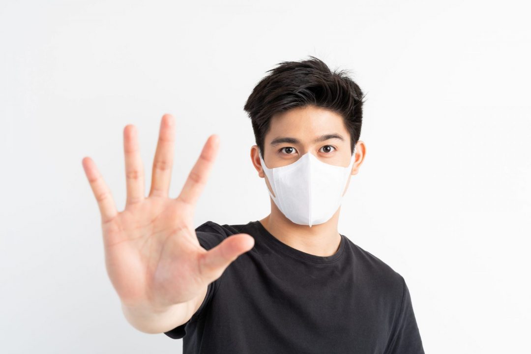 Stop Civid-19 , Asian man wearing Face Mask show stop hands gesture for stop corona virus outbreak , protect spread Covid-19 Coronavirus concept