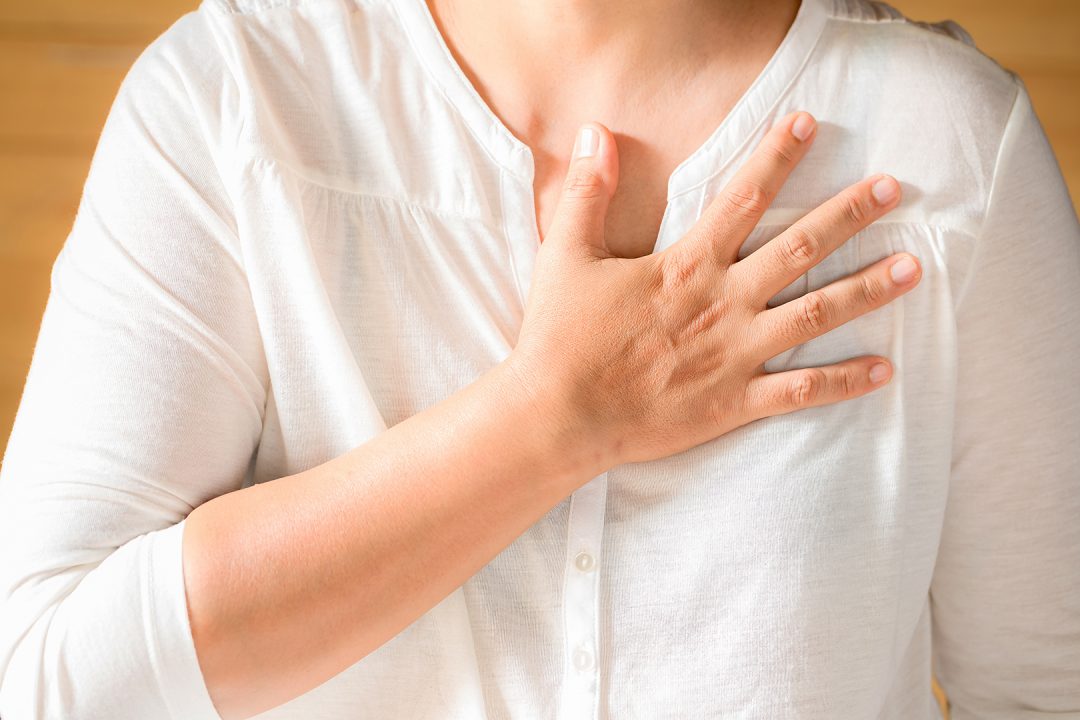 Woman is clutching her chest, acute pain possible heart attack